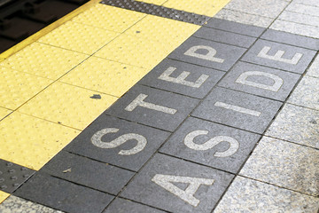 "Step aside" warning sign on ground in subway in New York