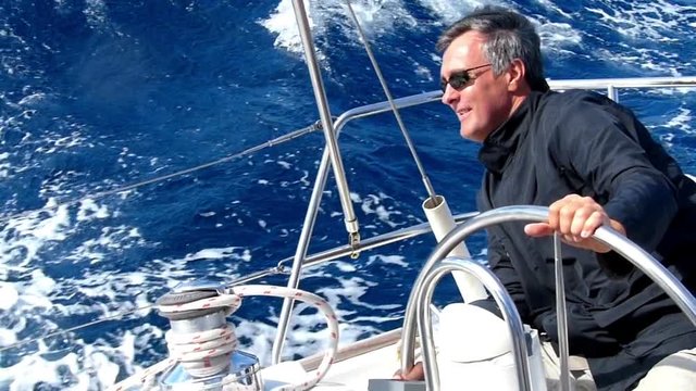 Mature adult skipper driving a sailboat. Slow motion and High speed camera.