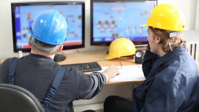Two workers talking about a job in a factory, controls the operation of devices in a power plant