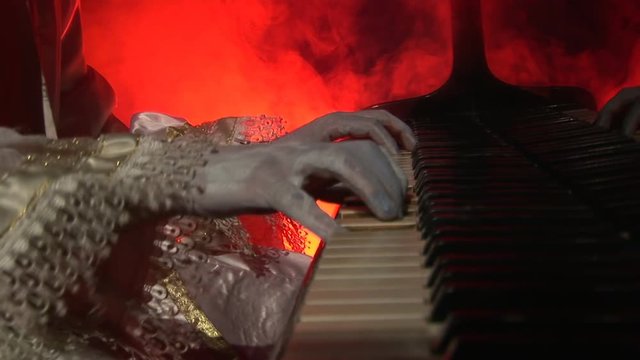 Man's hands an old, antique piano with strong, dramatic lighting and smoke.Unrecognizable person