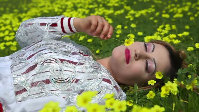 Middle-Eastern model with authentic traditional clothing and authentic makeup resting at yellow flower meadow