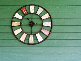 Old vintage clock on green wooden plank wall background.