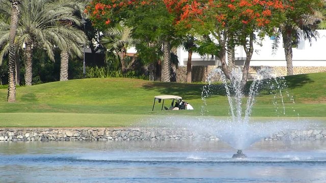 Perfect golf resort in Dubai city,shallow doff.Unrecognizable people in the background.Fountain water splashing in a front.