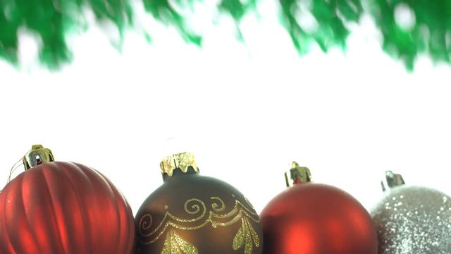 Decorative Christmas ornaments in lower third and a defocused green Christmas tree branch on top, white background area in the middle for text or photo gallery, seamless loop video