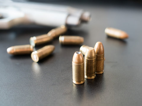 11mm bullets and short gun on black background. (selective focus)