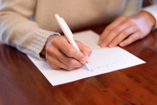 Woman sitting writing on a sheet of white paper