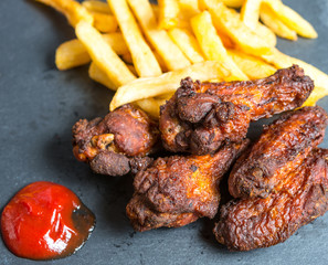 Chicken wings with sauce and golden French fries potatoes