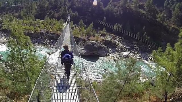 Rear view of male mountaineer on suspension bridge.High speed camera,slow motion