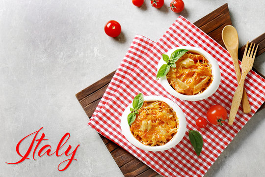 Delicious pasta Al Forno in bowls on napkin. Word ITALY on background. Italian food concept.