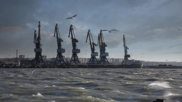 Video shot of cargo cranes with dramatic sky and storm wind in the sea port 
