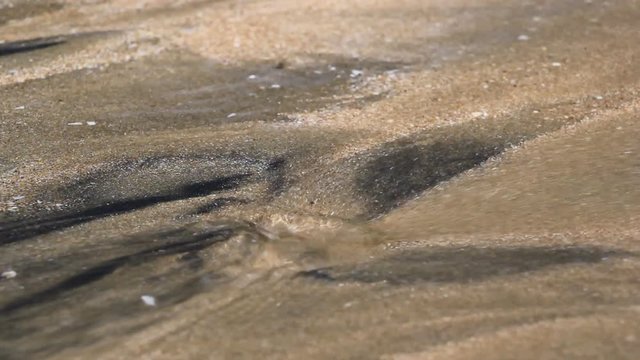Water spring in fine sand bed carrying sand along the flow and creating varying patterns