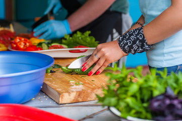 Women's hands cut fresh vegetables.