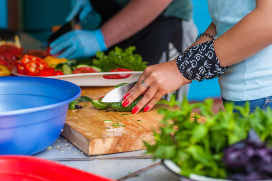 Women's hands cut fresh vegetables.