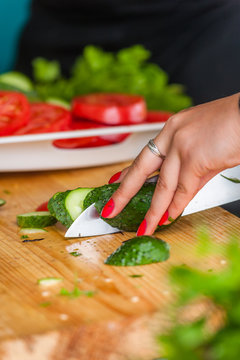 Women's hands cut fresh vegetables.