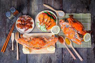 Heerlijke gegrilde zeevruchten (jumbo krabben, garnalen, inktvis) met kruiden op houten tafel