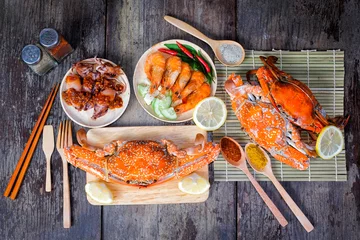 Keuken foto achterwand Schaaldieren Heerlijke gegrilde zeevruchten (jumbo krabben, garnalen, inktvis) met kruiden op houten tafel