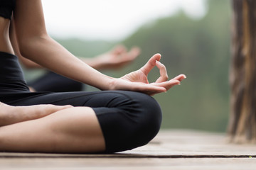 close up hand and soft focus of young people do yoga near the lake