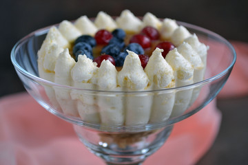 Individual festive dessert in glass. Soft cake and caramel surrounded by a crown of whipped cream. Cranberries and blueberries give an unforgettable taste. Perfect for parties. It melts in your mouth.