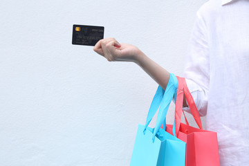 Woman holding shopping bag and credit card on white background