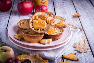 Obraz na płótnie Canvas Delicious Tartlets mini tarts pie with pumpkin and apple for Halloween in a pink plate on wooden background