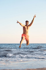 Fototapeta na wymiar Happy man jumping on beach