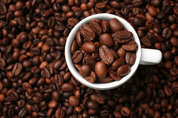 White cup and coffee beans, close up view