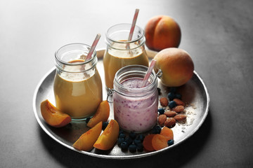 Mason jars with smoothie and some ingredients on grey table