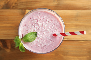 Delicious strawberry milkshake with mint on wooden background