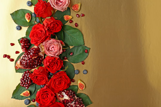 Composition of roses, figs, blueberries and pomegranate pieces on color background