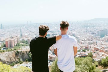 Two young men looking at the views form the top of a mountain.