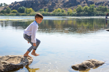 Small boy playing on rocks at the lake