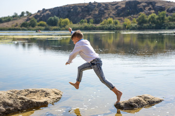 Young boy leaping from rock to rock