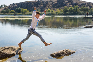 Young boy leaping from rock to rock