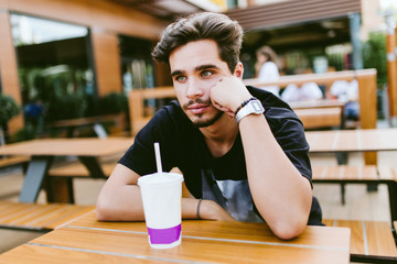 Handsome young man drinking refreshment at outdoor bar.