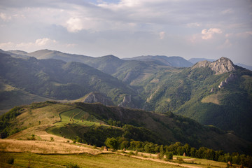 Fototapeta na wymiar Amazing Romanian countryside in mountains with haystacks on pasture in the summer afternoon light