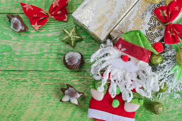 Christmas decorations, Santa Claus and chocolate. Old green wooden background, place for inscription.