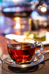 Black tea in glass Cup and glass teapot with a candle stands on