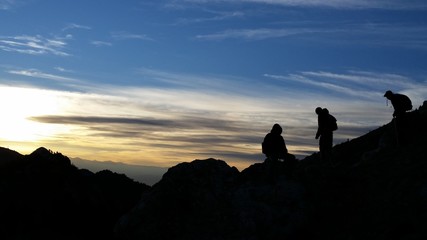 Silhouette of hikers on a ridge in the mountains at sunrise