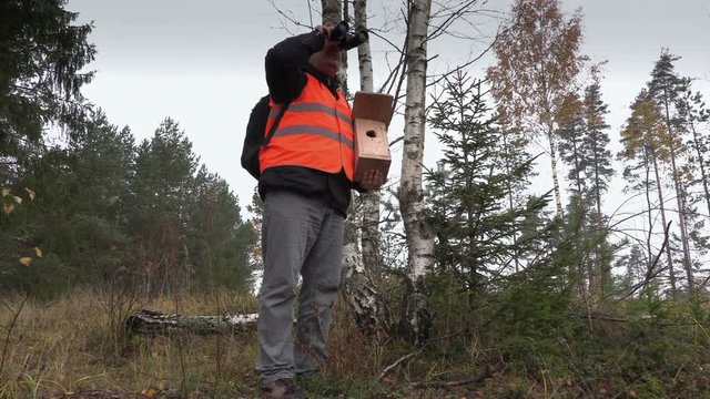 Ornithologist with binoculars and bird nesting box