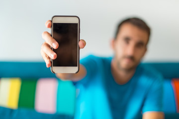 Man in his apartment showing his phone