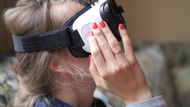 Young woman using VR-helmet at home. Handheld shot