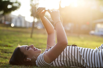 Young woman using smartphone in park in sunset