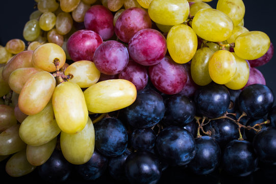 Pink, White And Black Grapes. On A Black Background.