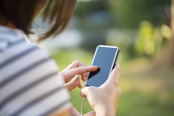 Young woman using smartphone in park in sunset