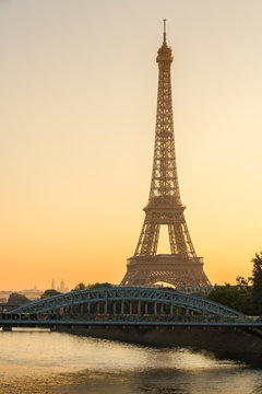 Warm sunrise light on the Eiffel Tower and the Seine River in Paris, France. The view includes the Pont Rouelle bridge and in the distance, the Basilica of the Sacred Heart (Sacre Coeur).