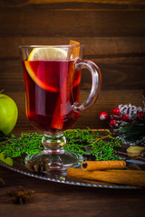 Mulled wine in a cup. Christmas set. Fruits and spices. On a wooden background.