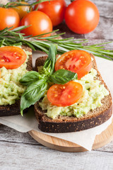 Avocado toast, cherry tomato on wooden background. Breakfast with toast avocado, vegetarian food, healthy diet concept.