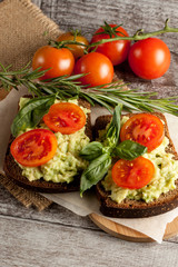 Avocado toast, cherry tomato on wooden background. Breakfast with toast avocado, vegetarian food, healthy diet concept.