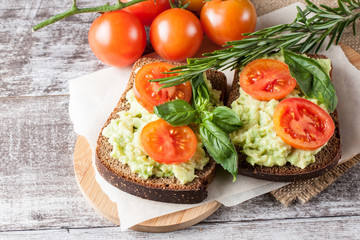 Avocado toast, cherry tomato on wooden background. Breakfast with toast avocado, vegetarian food, healthy diet concept.