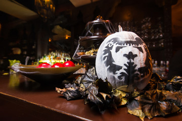 Decorated pumpkin on table/Decorative pumpkin,leaves and plate with red apples on a table at Halloween party.Selective focus